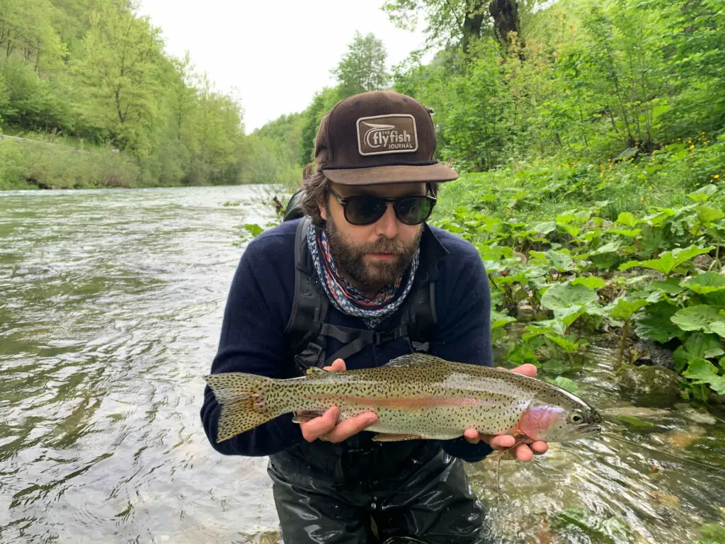 Fly fisherman holding a rainbow trout