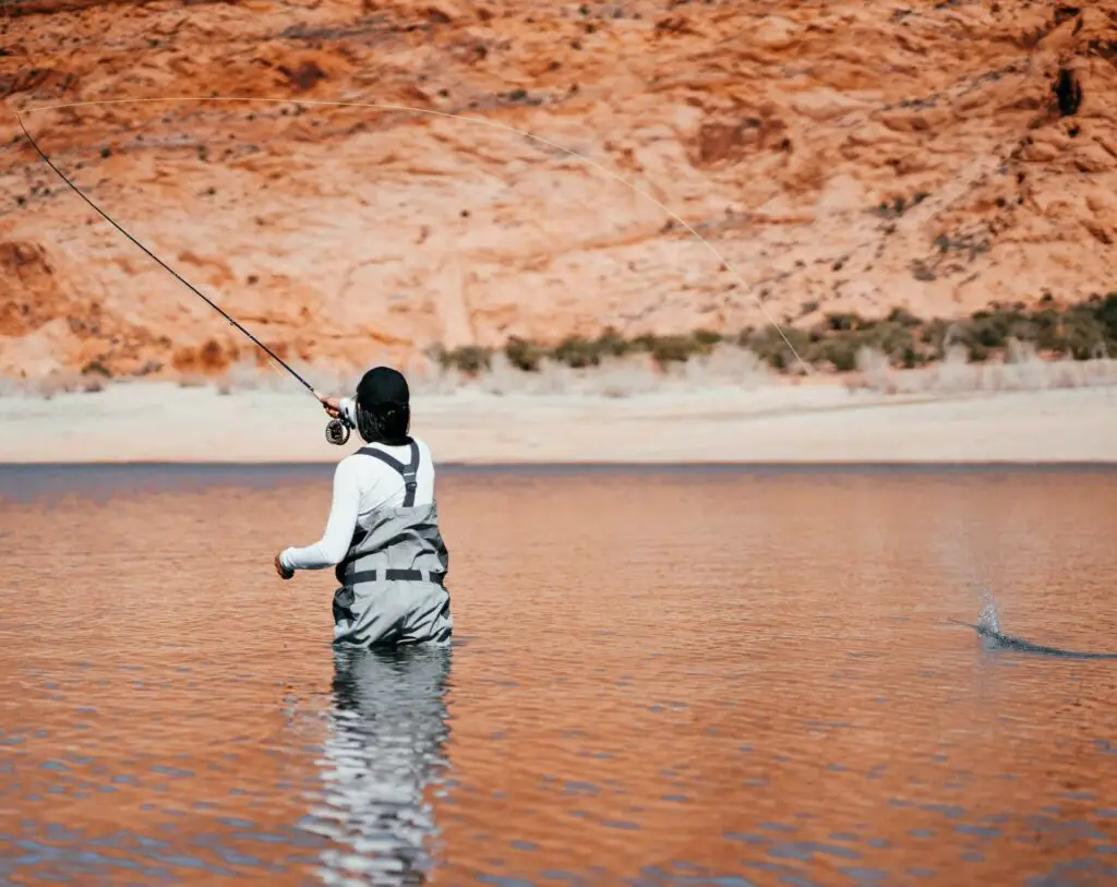 Woman fly fishing in a river casting a rod