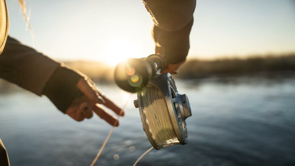 A fly fisherman casting a fly rod and reel. Review of the best fishing neck gaiters