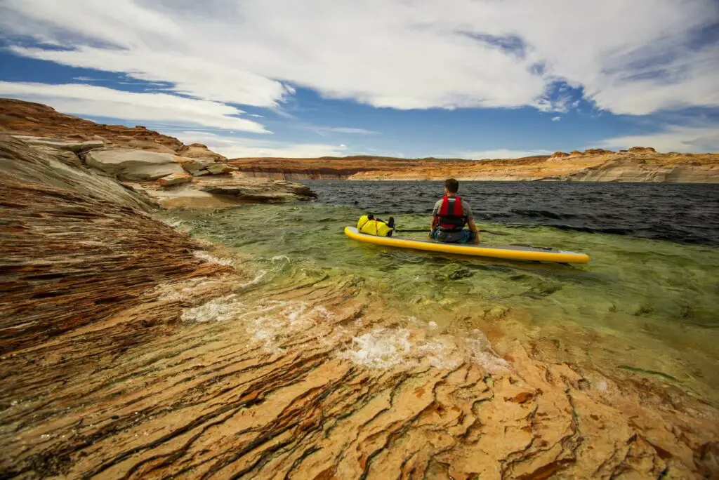 Man on a SUP wearing a life vest for kayak fishing