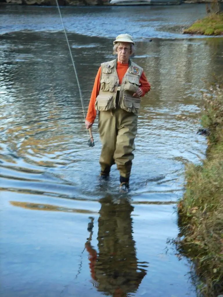 Woman holding a fly rod walking in a river