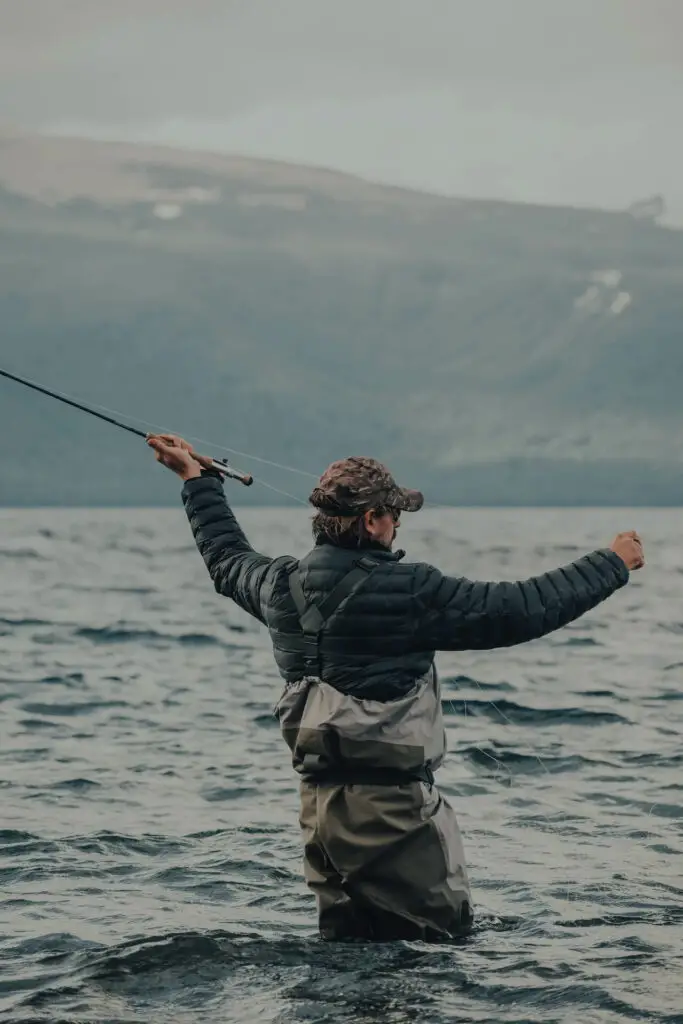 Fly fisherman casting a rod in the water - Review: Best Puffer Jacket for Fishing