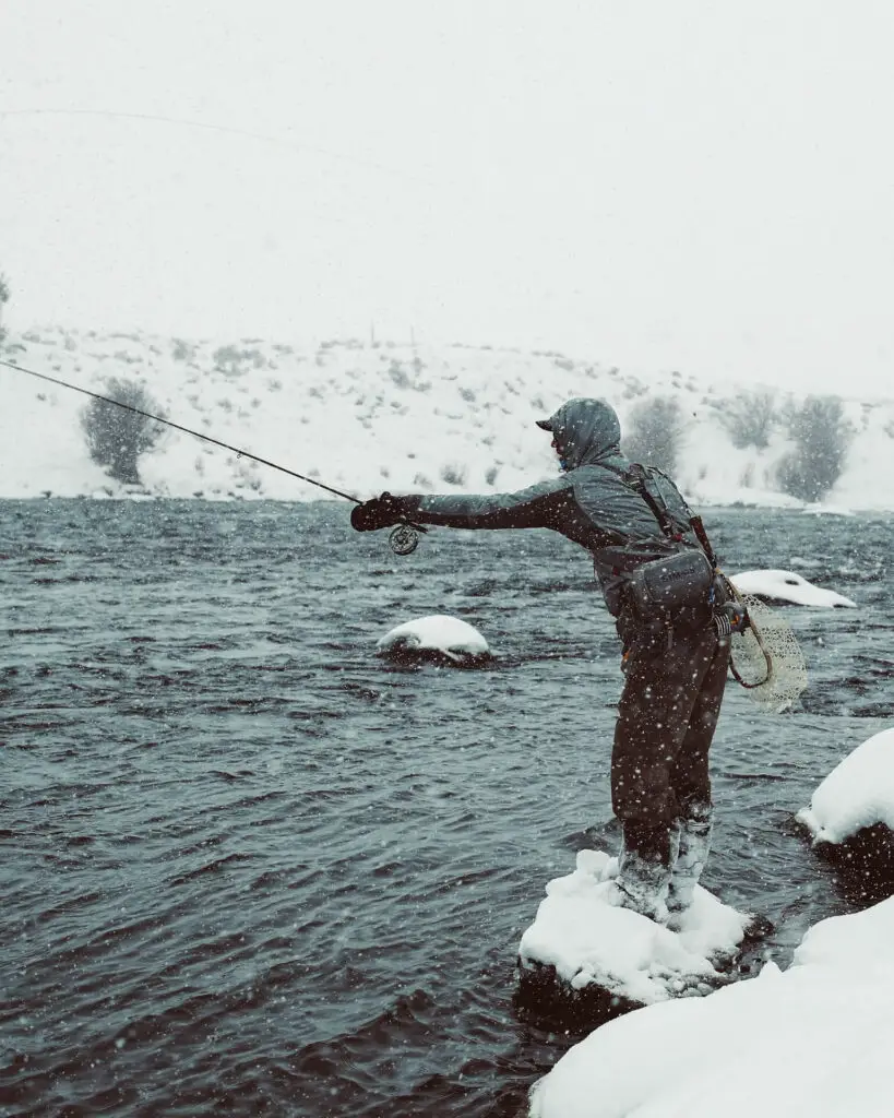 Reaching far to fly fish a river in winter