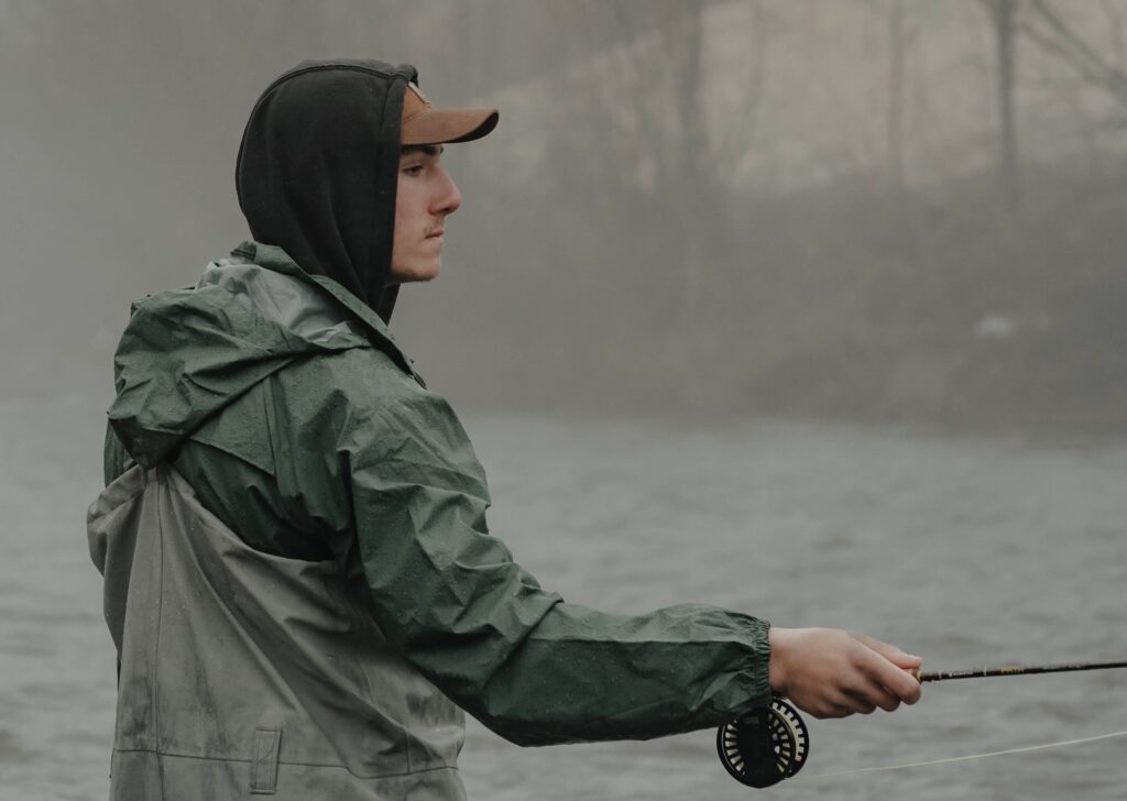 Fly fisherman in a river wearing a fly fishing hoody