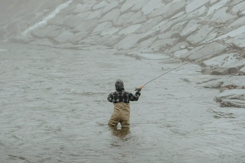 Fly fisherman in a river wearing a fly fishing hoody