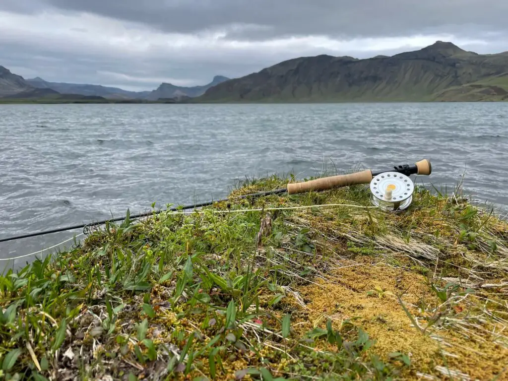 VR Trutta Perfetta Fly Reel on a rock and lake in background