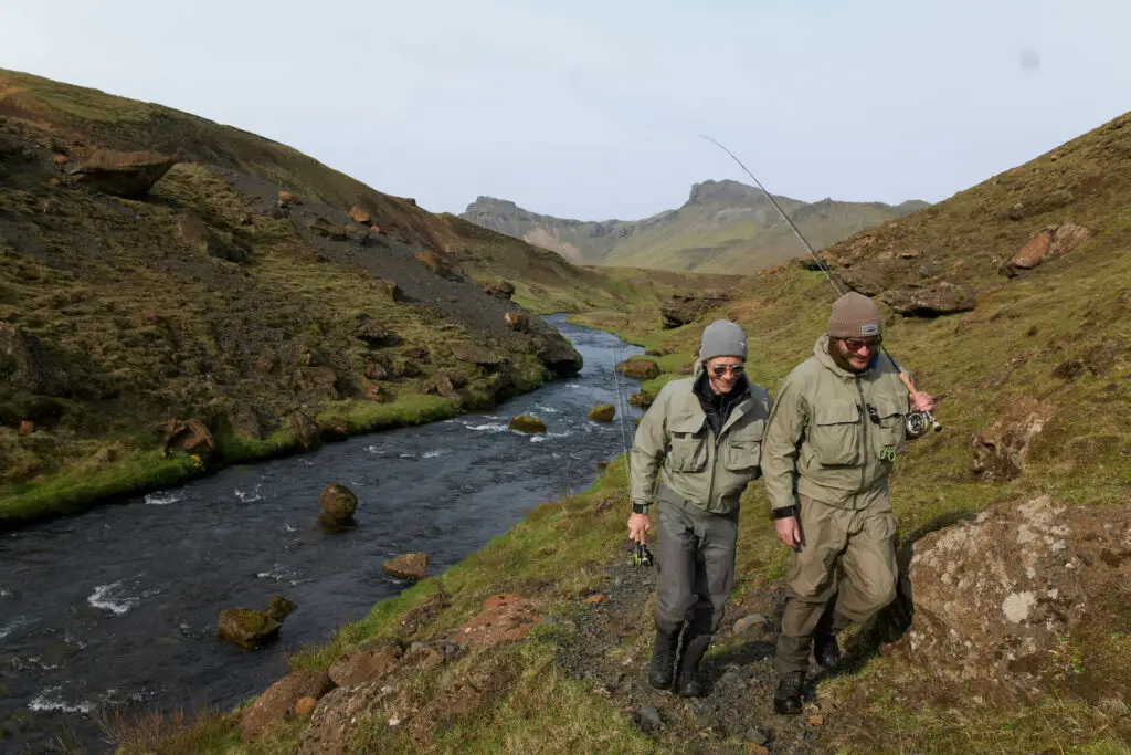 fly fishermen walking along a river bank