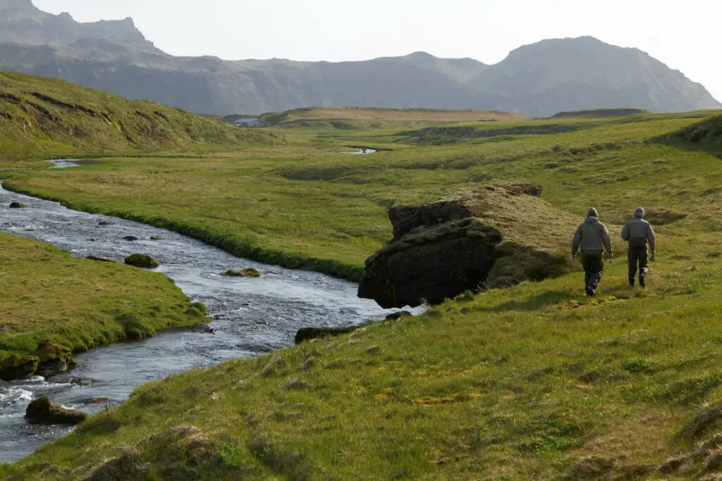 fly fishermen walking along the bank of a river