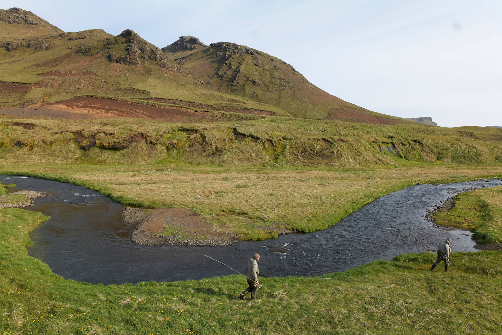 Wild river in Iceland and fly fishermen walking along the bank