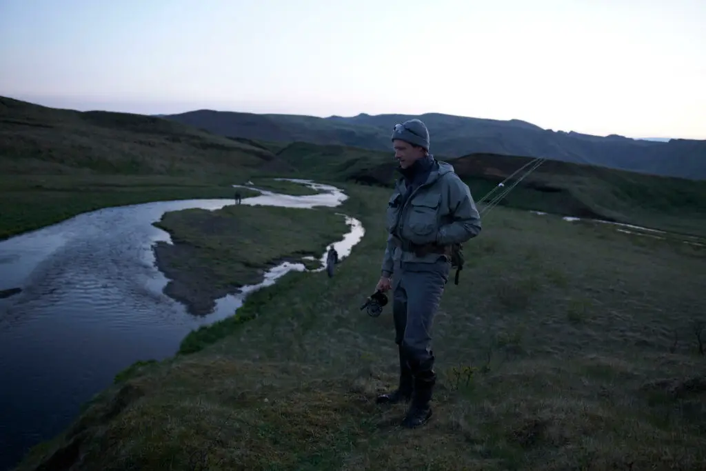 fly fisherman with rod in hand looking into a river