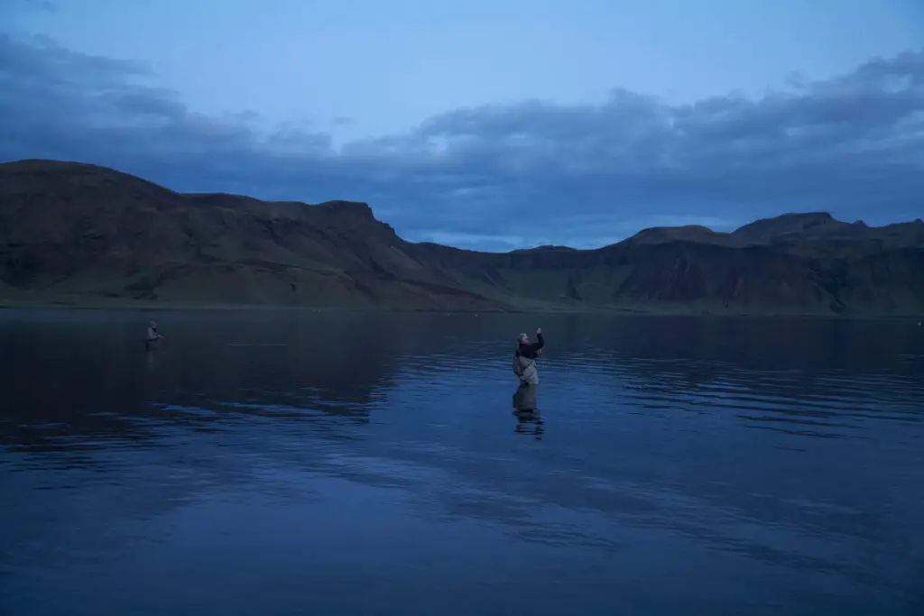 Fly fishermen fishing a lake at night