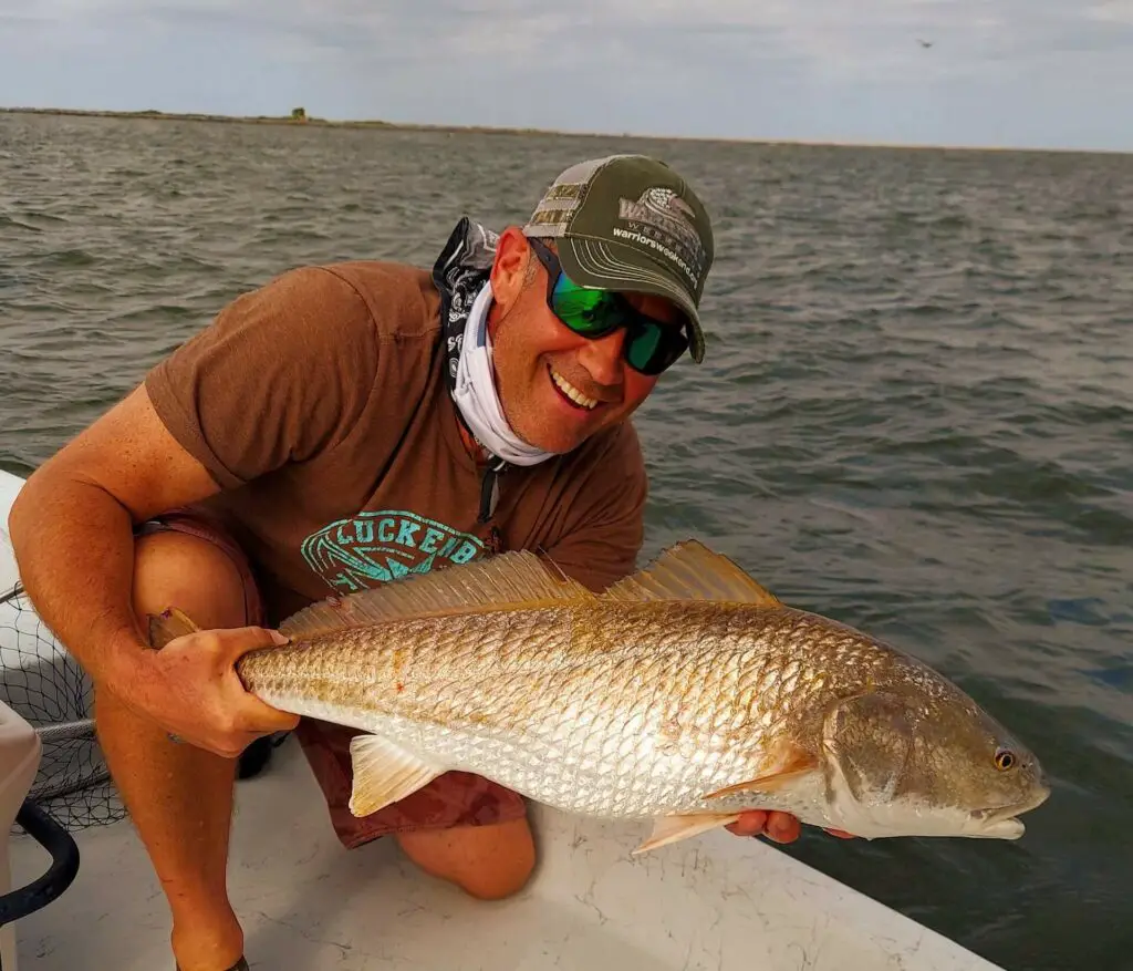 Fly fisherman holding a redfish on a boat