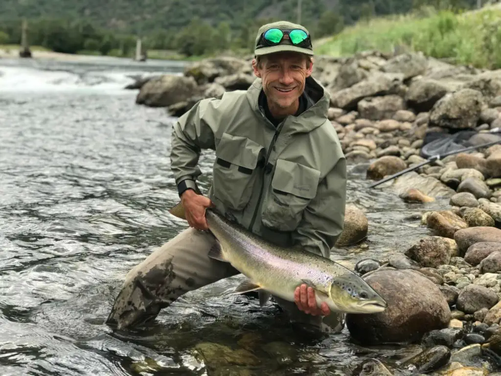 Fly fisherman with salmon in hand wearing the Oakley Clifden Polarized Fishing Sunglasses