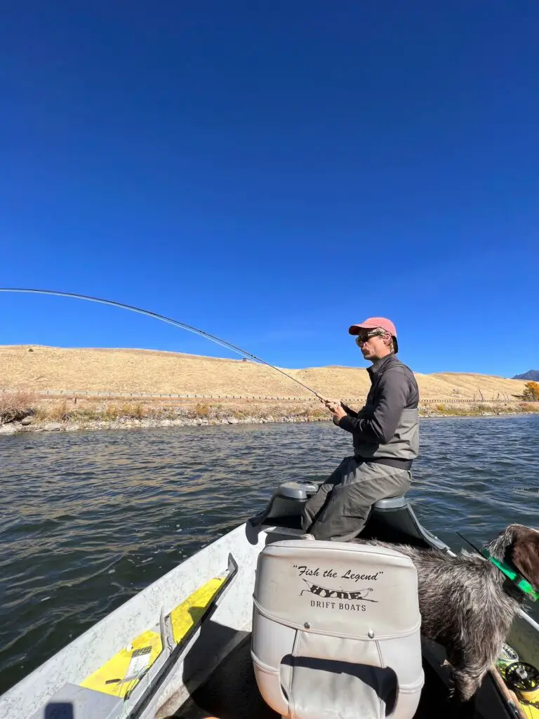 Fly fisherman playing a fish fishing from a boat wearing fly fishing waders