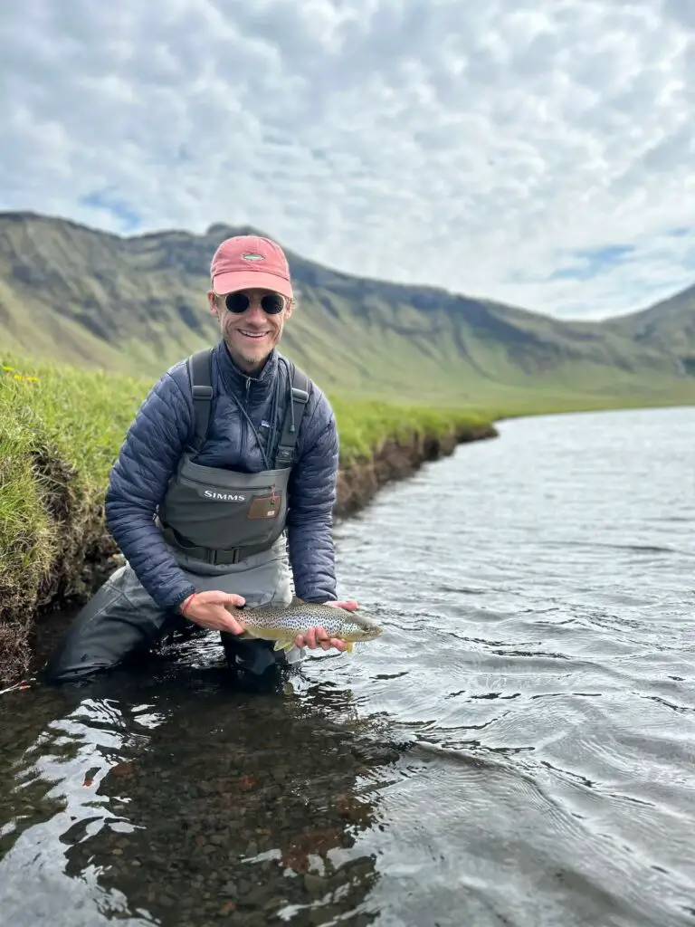 Brown trout in hands of a fly fisherman wearing the Simms G3 Waders