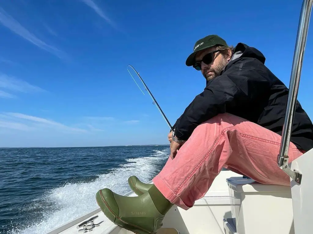 Fly fisherman on a boat wearing the Simms Challenger Deck Boot
