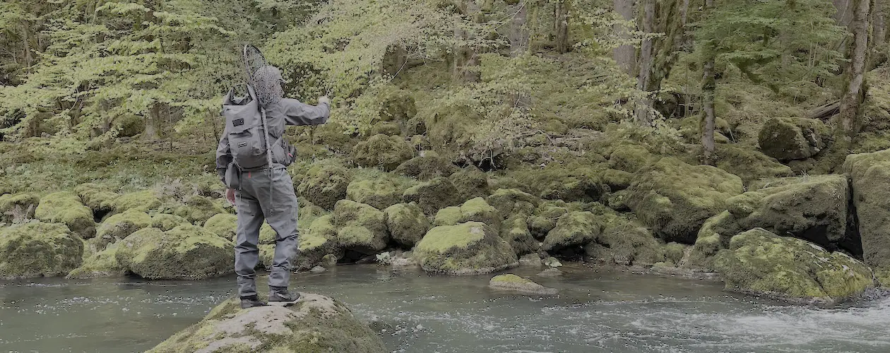 Fly fisherman fishing from a rock wearing the Guideline Experience Backpack