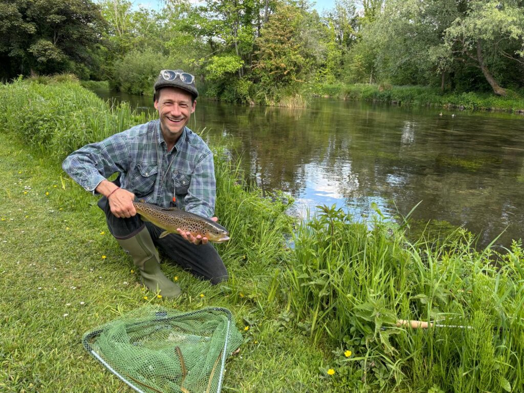 Fly fisherman at river with trout in hand