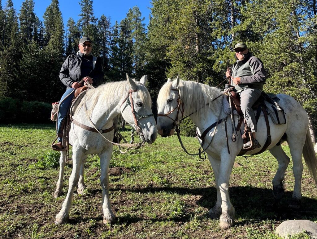 Jim Schmiedeskamp and Lou Perlaky riding draft horses into the Thorofare